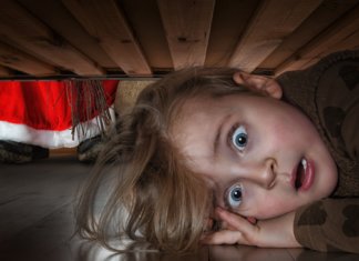 Frightened baby hiding under the bed