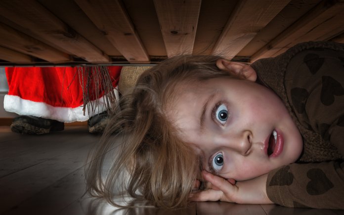 Frightened baby hiding under the bed