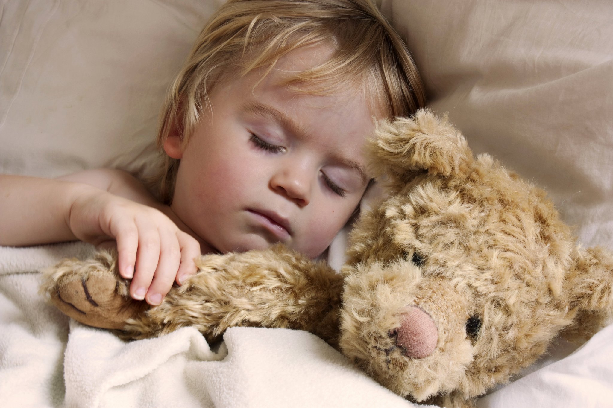 Baby boy sleeping with a teddy bear