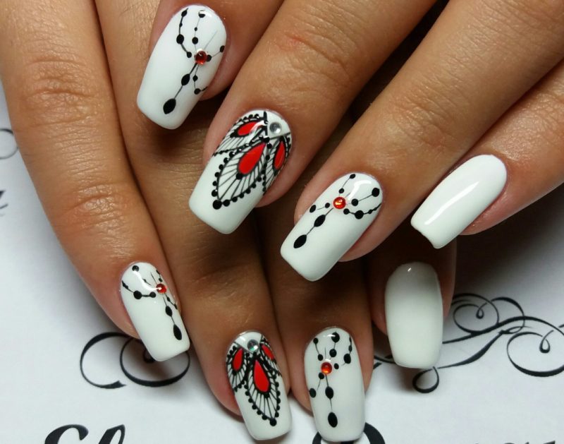 White nails with black and red patterns