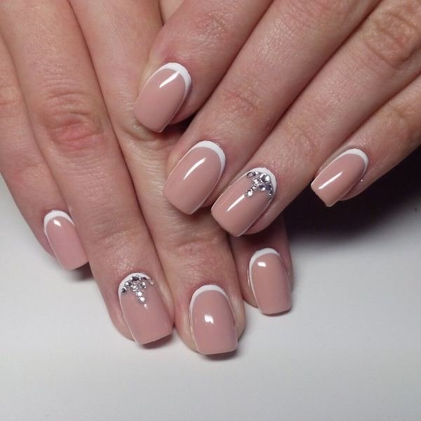 Nude style manicure with white holes and rhinestones.