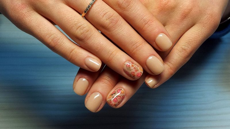 Beige manicure with floral slides.