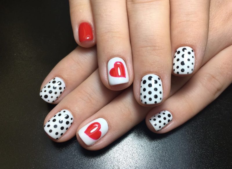 White manicure with black dots and a heart.