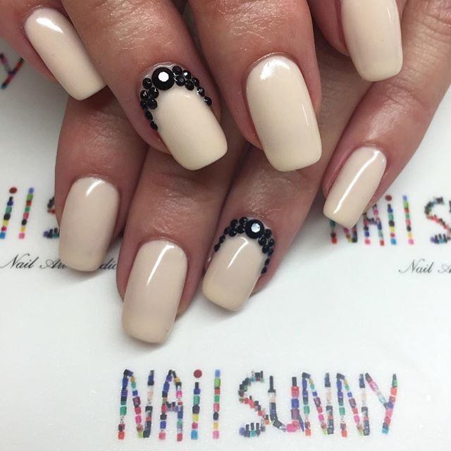 Nails with nude varnish and black rhinestone holes