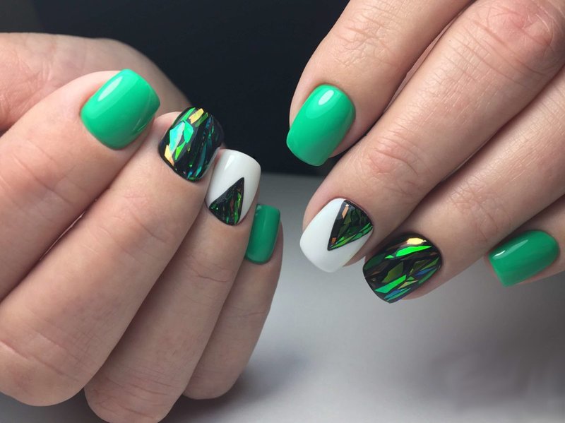 Green manicure with broken glass and a triangular hole