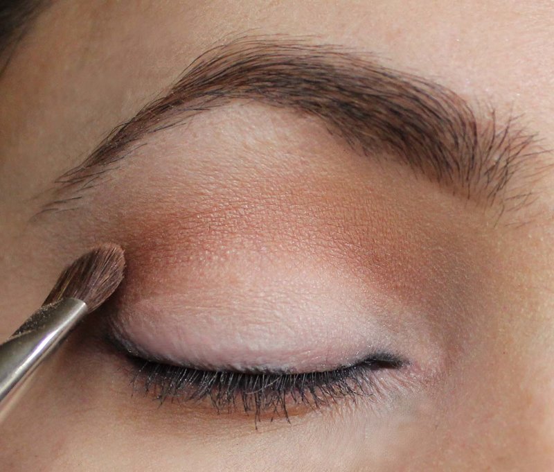 Applying bronze eyeshadow to the crease between the eyelids