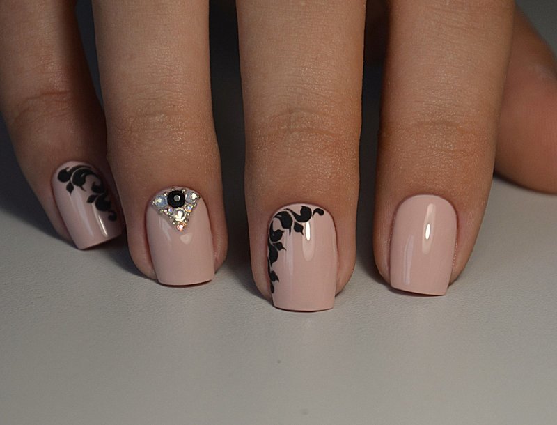 Nude manicure with black patterns and rhinestones