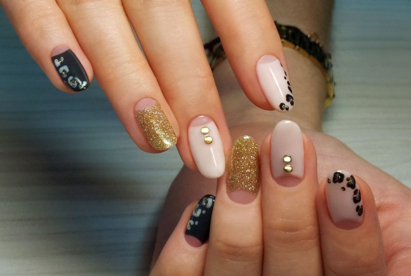 Gold glitter nude manicure with jewelry and leopard print.