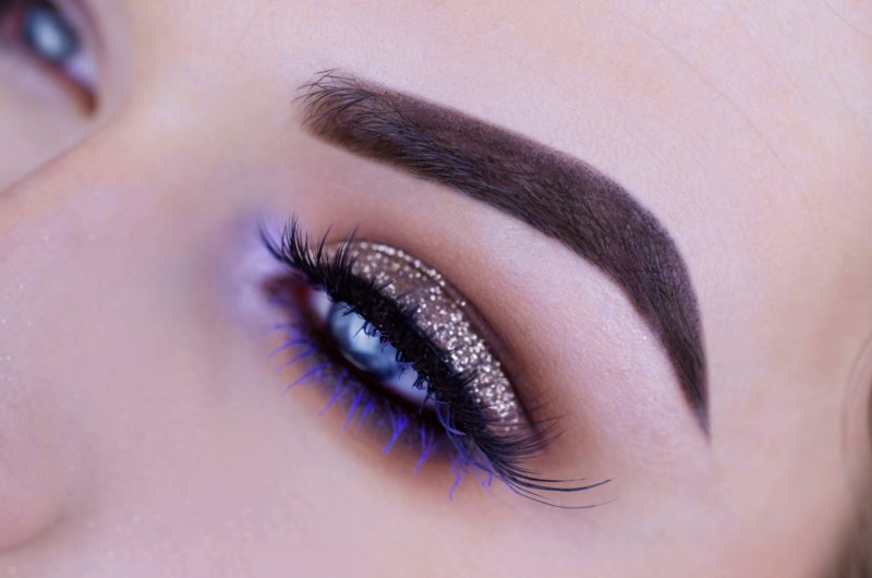 Golden make-up with glitter and purple mascara