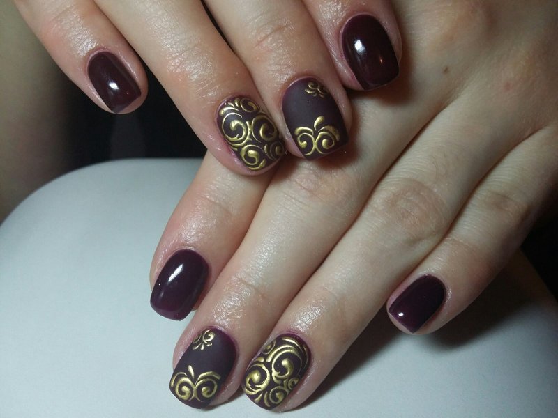 Burgundy manicure with gold monograms.