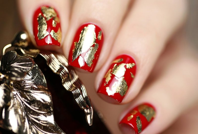 Red manicure with gold leaf