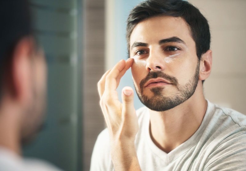 A man applies cream on his face