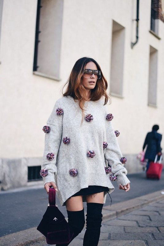 Girl in oversized sweater with pompons.