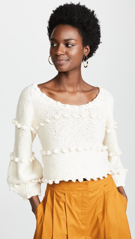 Girl in a sweater with pompons and a skirt