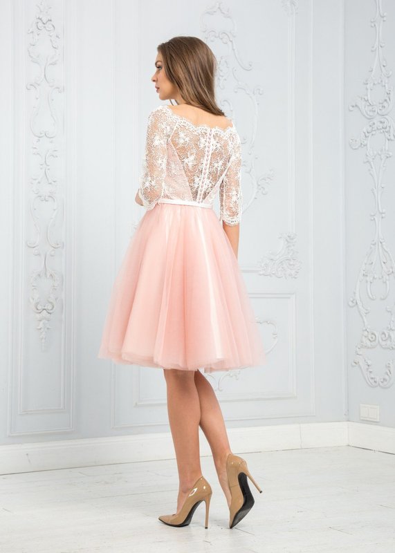 A girl in a soft pink cocktail dress with lace on her back