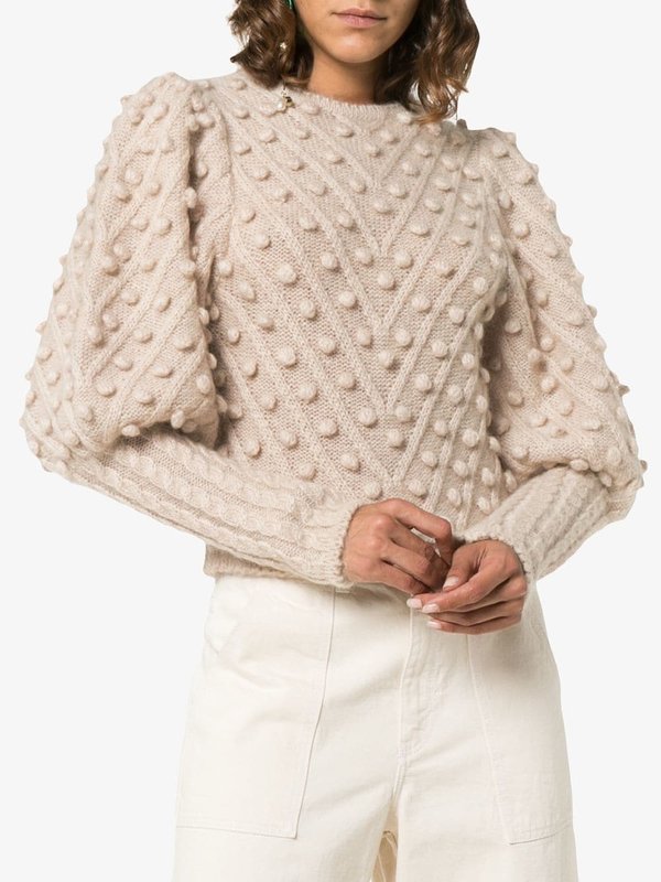 Girl in a beige sweater with pompons.