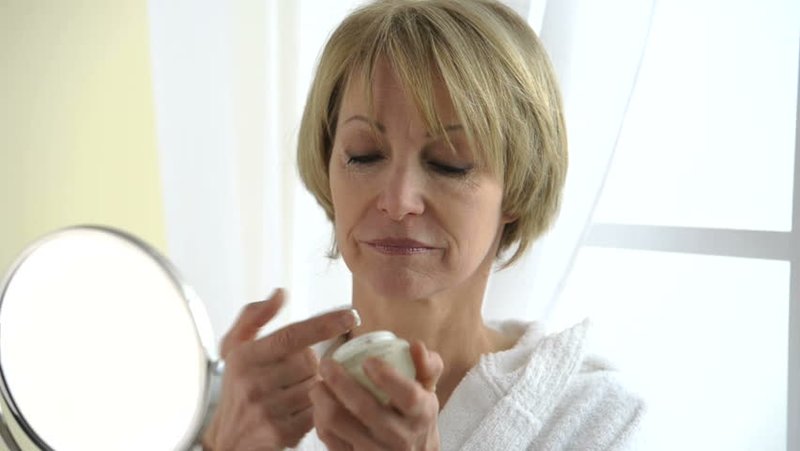 Woman after 50 moisturizes her face