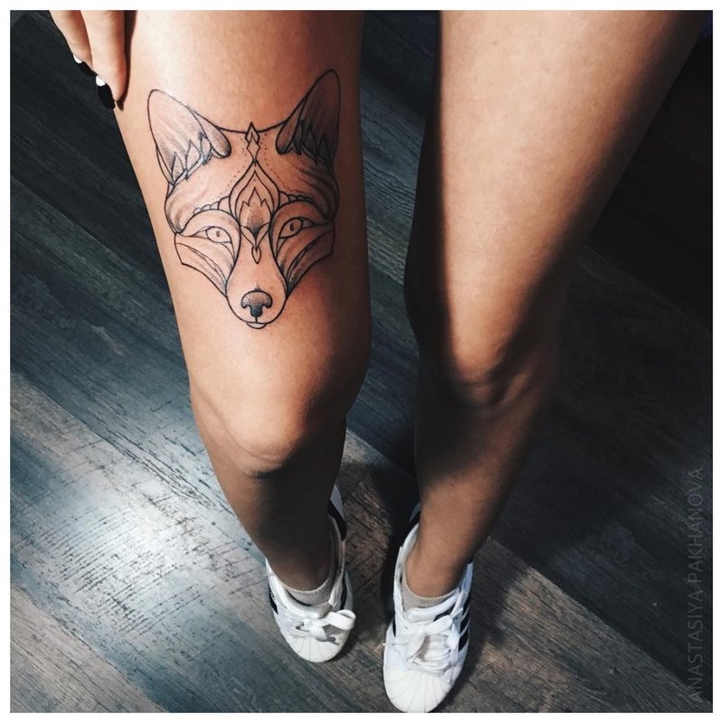 Wolf face - tattoo on the girl’s leg