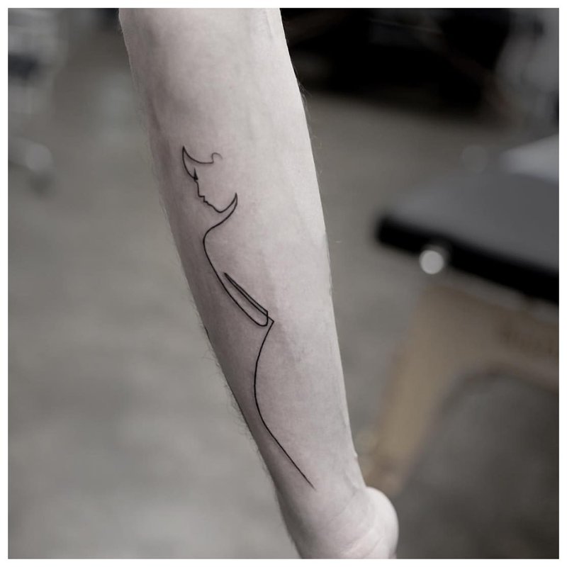 Woman silhouette - tattoo on man’s arm