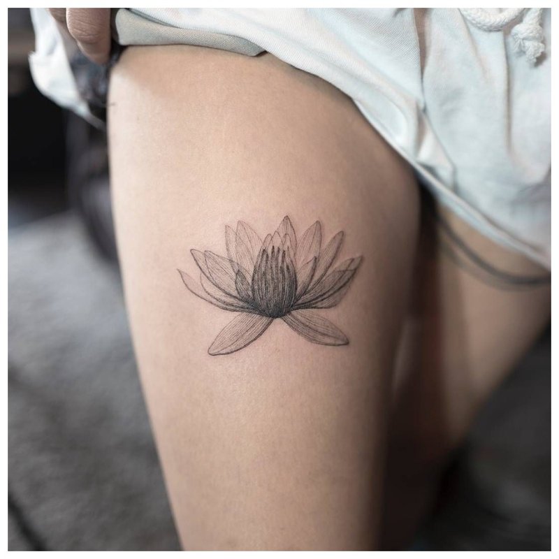 Delicate flower - tattoo on the girl’s leg