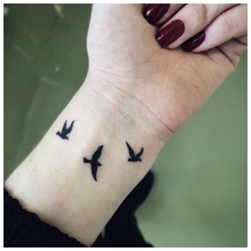 Tattoo in the form of birds on the girl's hand