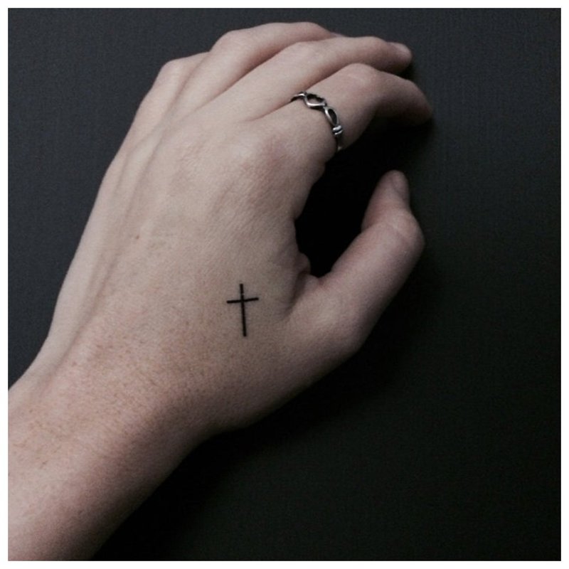 A small tattoo on the man’s arm in the form of a cross