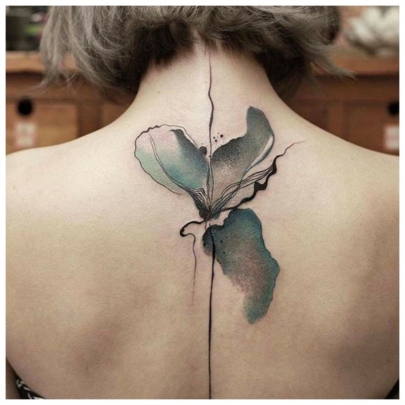 Watercolor tattoo in the form of a flower between the shoulder blades