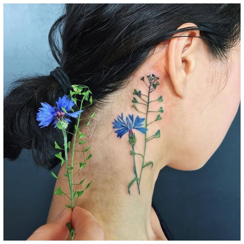 Delicate flower tattoo on the girl's neck