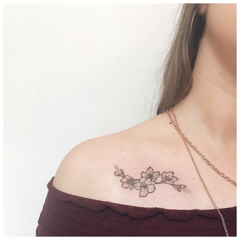 Contour flower tattoo under the collarbone