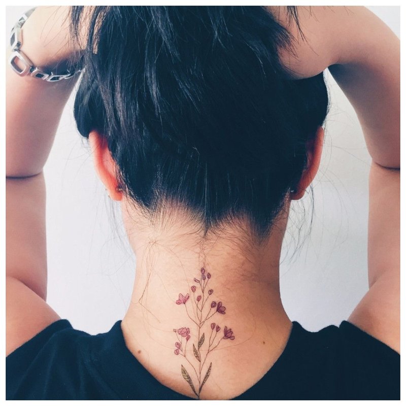 Delicate flower tattoo on the girl's neck