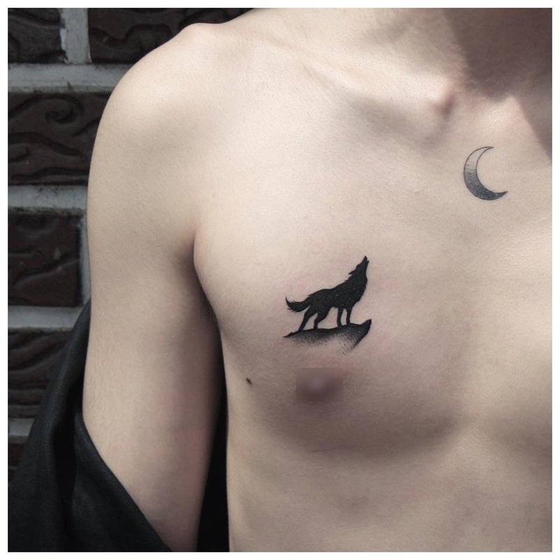 A wolf howls at the moon - a tattoo on a man’s chest